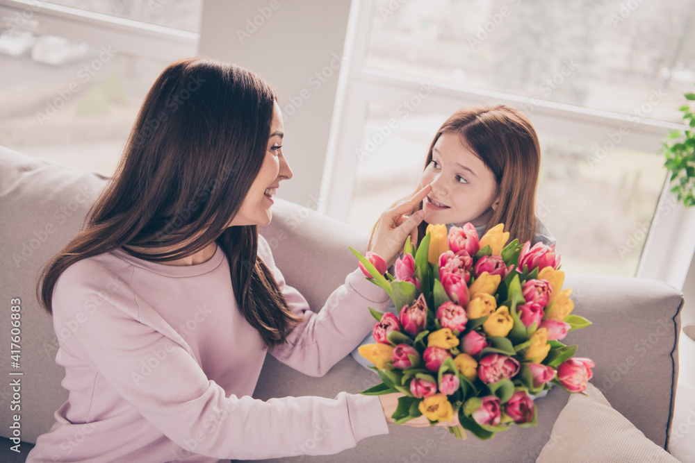 Photo of optimistic brunette red hairdo mom daughter gift flower on sofa wear sweater at home Photo of optimistic brunette red hairdo mom daughter gift flower on sofa wear sweater at home