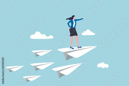 Business leadership, woman power to lead company to achieve target, smart confidence businesswoman standing on leading flying paper airplane origami pointing finger to the direction to reach goal. photo