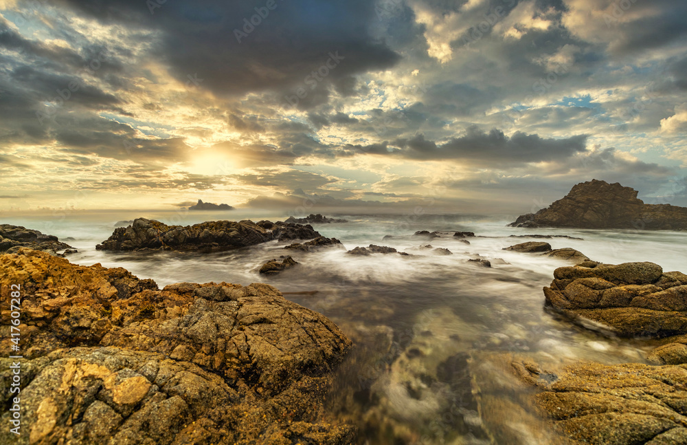 Beautiful seascape, ocean views, rocky coastline, sunlight on the horizon. Composition of nature. Sunset scenery background. Cloudy sky. Reflection of water. California coast. Shot with a long