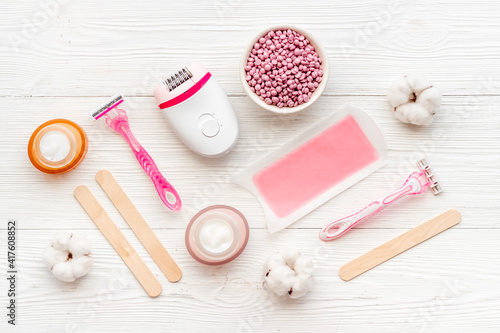 Flat lay of pink epilator with wax strips and razor. Spa cosmetic treatments.