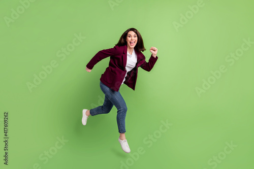Full size profile photo of optimistic brown hairdo lady jump wear cardigan jeans sneakers isolated on green background