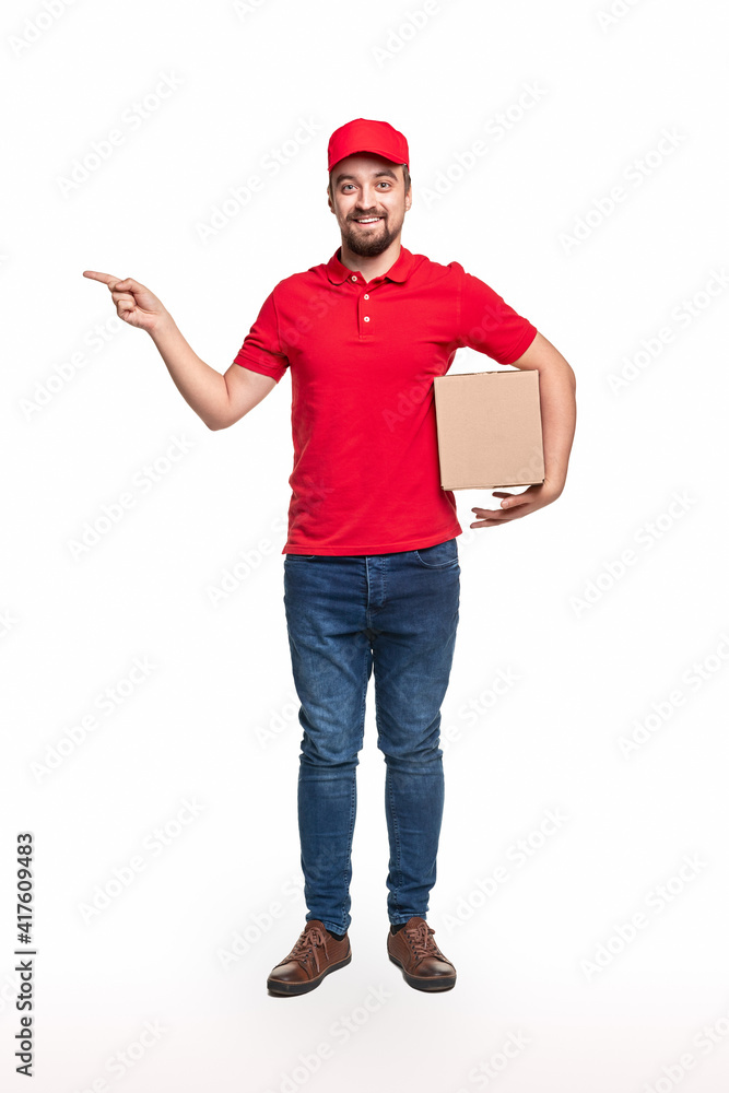 Cheerful courier with parcel pointing aside