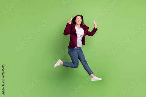 Full size profile photo of hooray brown hairdo lady jump show v-sign wear cardigan jeans sneakers isolated on green background