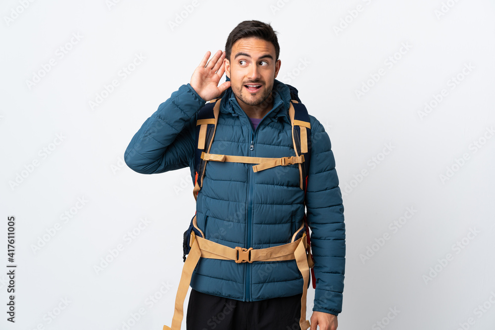 Young mountaineer man with a big backpack isolated on white background listening something Young mountaineer man with a big backpack isolated on white background listening something