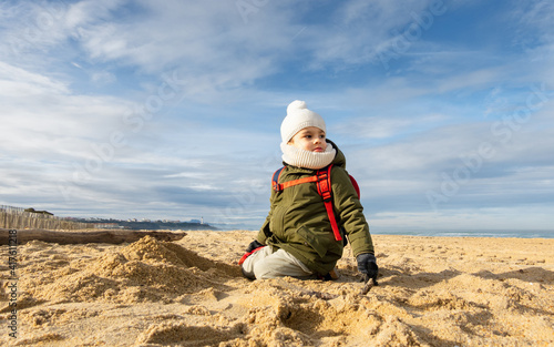 Little boy looking away on beach, beautiful winter season