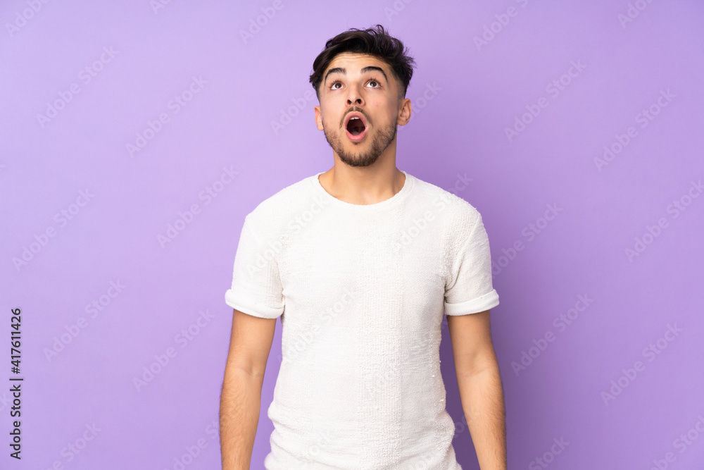 Arabian handsome man over isolated background looking up and with surprised expression Arabian handsome man over isolated background looking up and with surprised expression