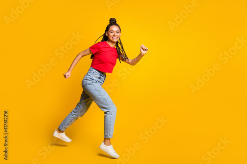 Full length body size profile side view of lovely cheerful girl jumping running copy space isolated bright yellow color background