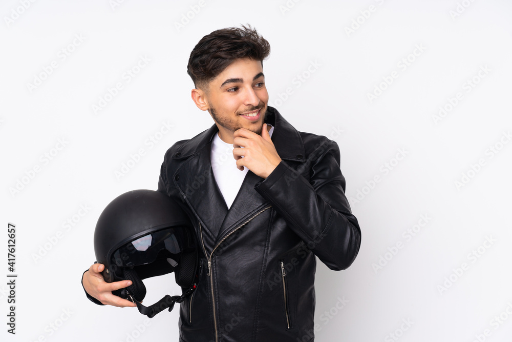 Arabian man with a motorcycle helmet isolated on white background thinking an idea and looking side Arabian man with a motorcycle helmet isolated on white background thinking an idea and looking side
