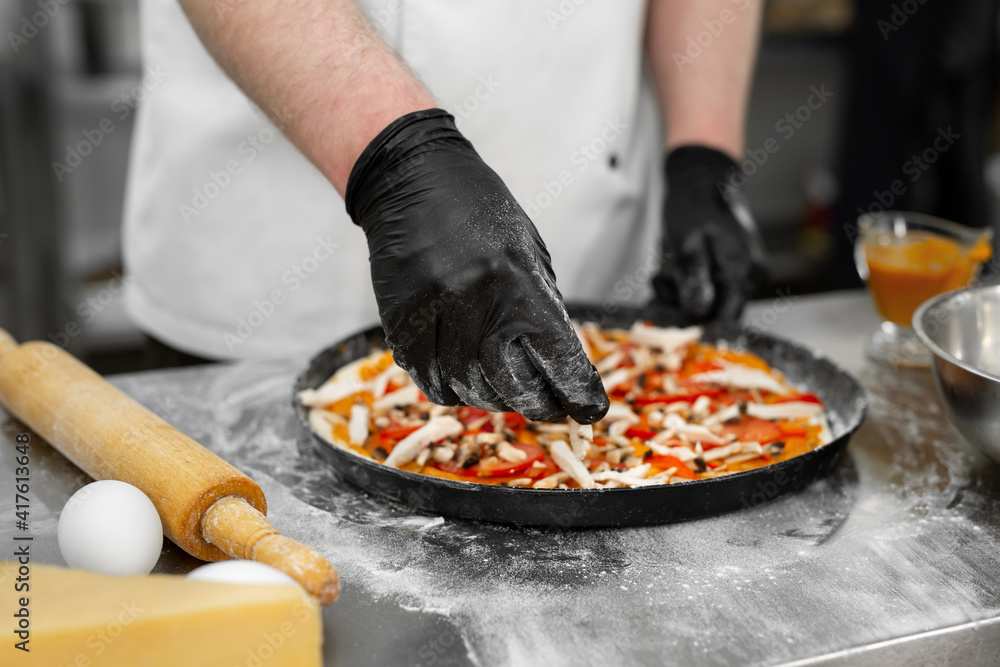Cooking pizza. Close-up of the cook's hand laying out the meat on the dough