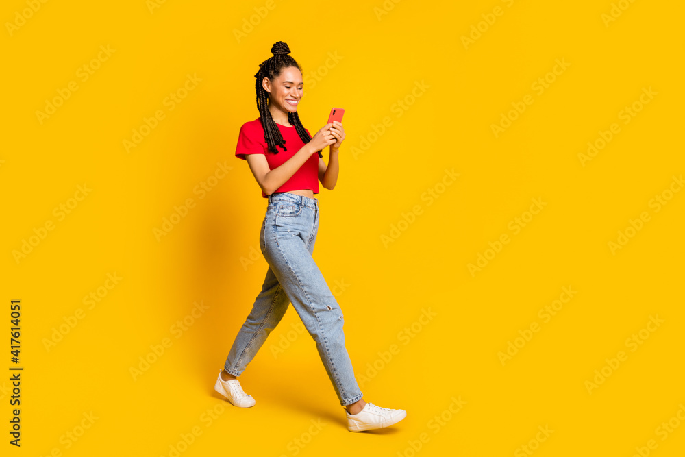 Full length body size view of lovely focused cheerful girl going using device app 5g isolated bright yellow color background Full length body size view of lovely focused cheerful girl going using device app 5g isolated bright yellow color background