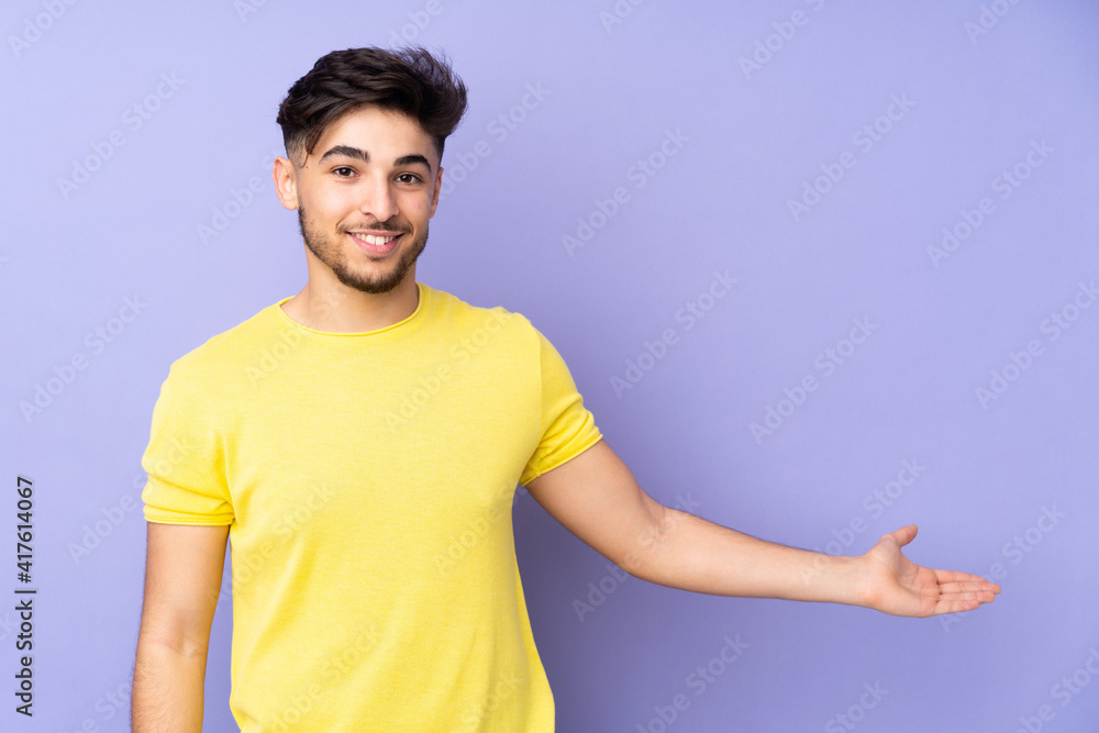 Arabian handsome man over isolated background extending hands to the side for inviting to come Arabian handsome man over isolated background extending hands to the side for inviting to come