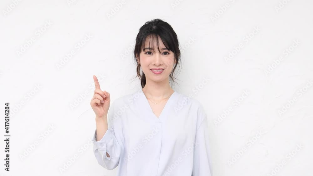 白い壁の前でポイントを示す若い女性 白い壁の前でポイントを示す若い女性