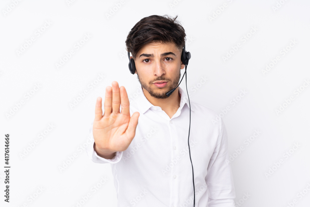 Telemarketer Arabian man working with a headset isolated on white background making stop gesture with her hand Telemarketer Arabian man working with a headset isolated on white background making stop gesture with her hand