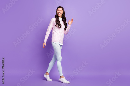 Full length body size view of pretty cheerful wavy-haired girl going waving hi hello isolated on violet color background