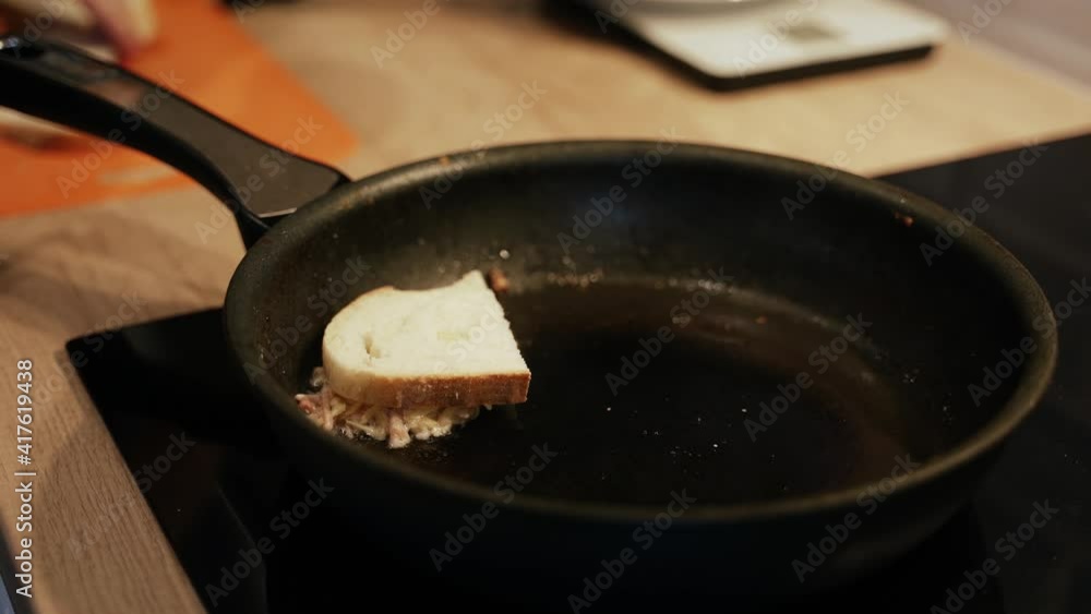 Cooking hot sandwiches in a pan. Working at home on a black plate. Close-up Cooking hot sandwiches in a pan. Working at home on a black plate. Close-up