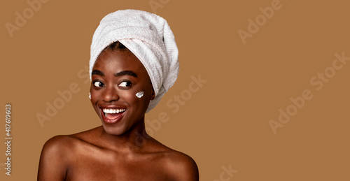 Cheerful african american woman with cream on cheek