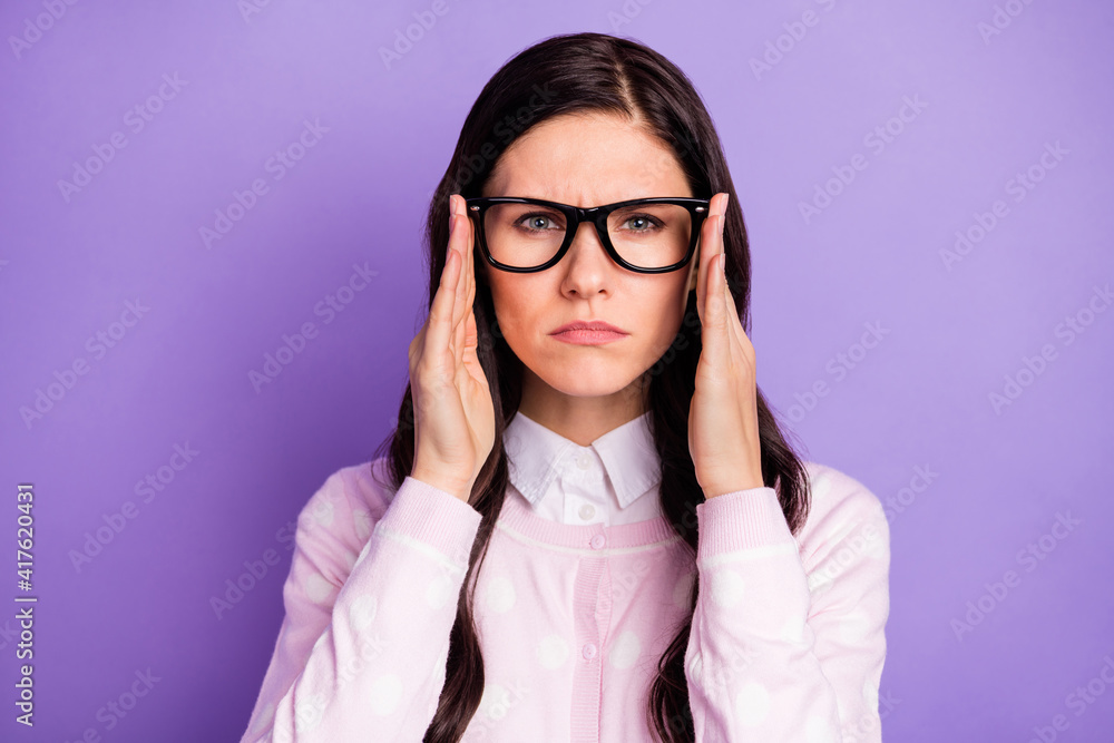 Portrait of attractive focused tense wavy-haired girl looking suspiciously touching specs isolated over violet color background Portrait of attractive focused tense wavy-haired girl looking suspiciously touching specs isolated over violet color background