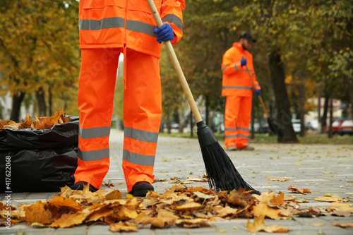 Street cleaners sweeping fallen leaves outdoors on autumn day, closeup