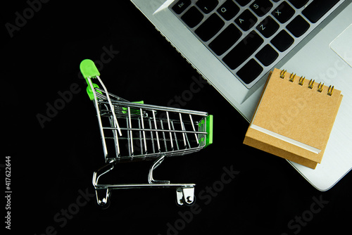 Top view shopping cart and Calendar on laptop with black background. Black Friday sale online shopping, Financial and Business Shopping. Technology, E-commerce concept.