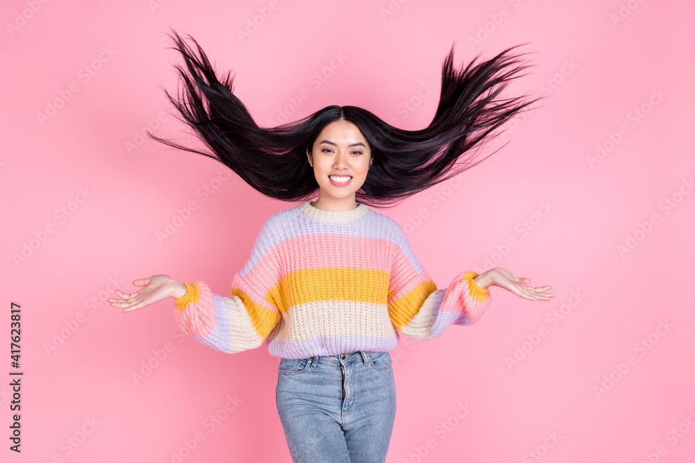 Photo of young beautiful smiling charming asian girl with flying hair advertising shampoo isolated on pink color background