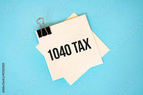 Text 1040 tax on sticky notes with copy space and paper clip isolated on red background.Finance and economics concept.