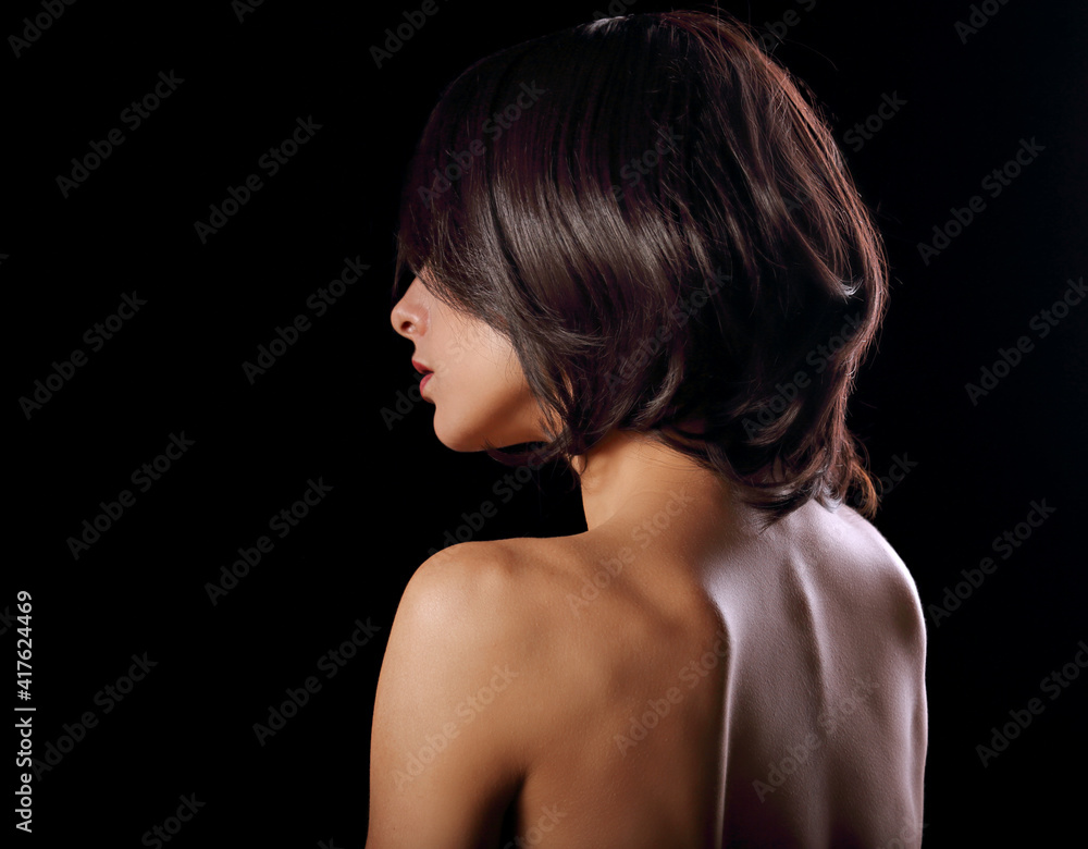 Alluring portrait of short bob hair style woman looking down on black background. Closeup portrait. Back side Alluring portrait of short bob hair style woman looking down on black background. Closeup portrait. Back side
