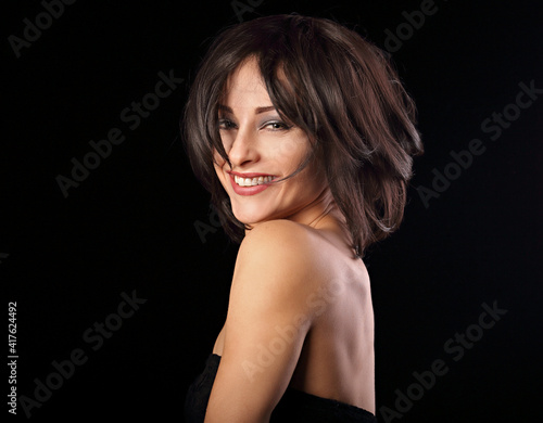 Happy laughing bright makeup woman shaking her black short hair on black background. Closeup portrait