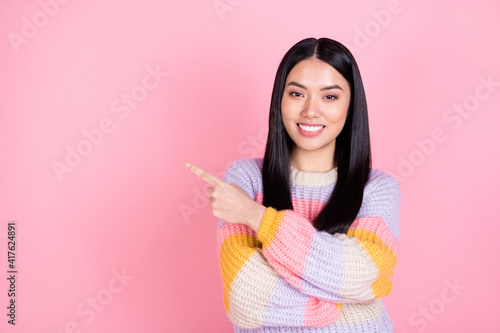 Photo of young charming sweet good mood smiling girl point finger copyspace promotion isolated on pink color background