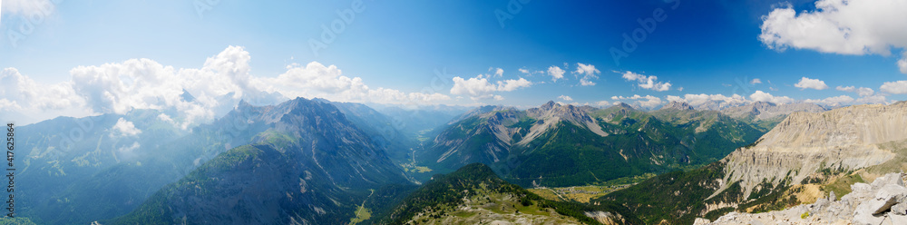 Fototapeta premium High altitude landscape in idyllic uncontaminated environment once covered by glaciers. Summer adventures and exploration on the Italian French Alps. Expansive view from above, clear blue sky.