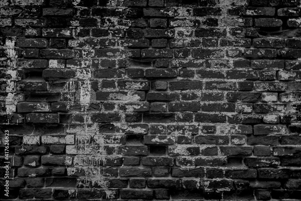 Fototapeta premium Texture of old dark scary dirty crumbling brick wall of ancient city. Uneven pitted surface of the brickwork of the damp basement with holes and worn. Decayed burnt brickwall background for 3D design