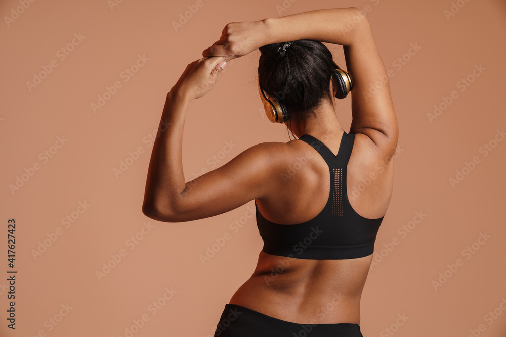 Obraz premium African american woman in headphones doing exercise while working out