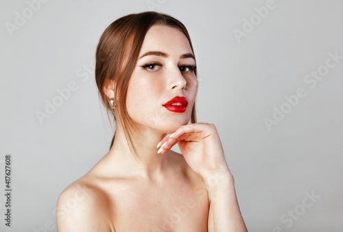 Face of the young pretty woman with a healthy skin. Beautiful face of young white woman with french manicure nail. Fashion makeup and care for hands , nails and cosmetics .