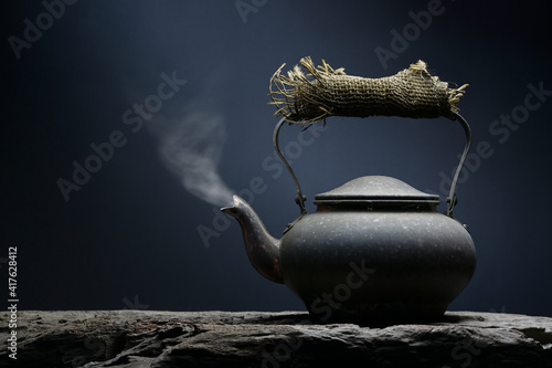 Black metal tea or coffee kettle close-up with hot steam coming out the spout still life fine art.