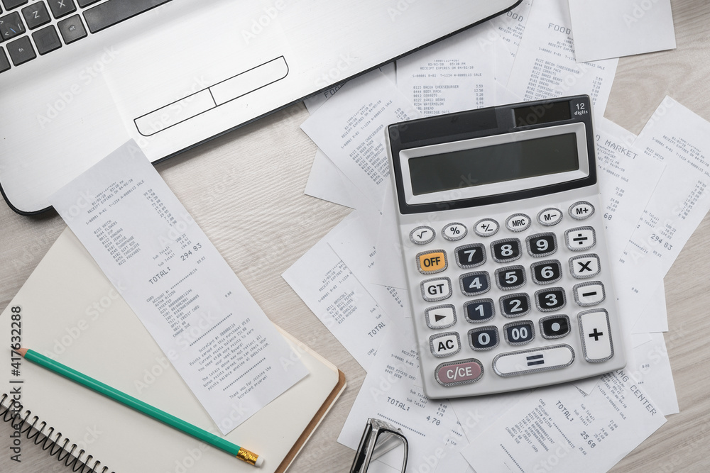 Man hand using calculator and writing make note with calculate about cost and taxes at home office. Businessman doing some paperwork in the workplace Man hand using calculator and writing make note with calculate about cost and taxes at home office. Businessman doing some paperwork in the workplace