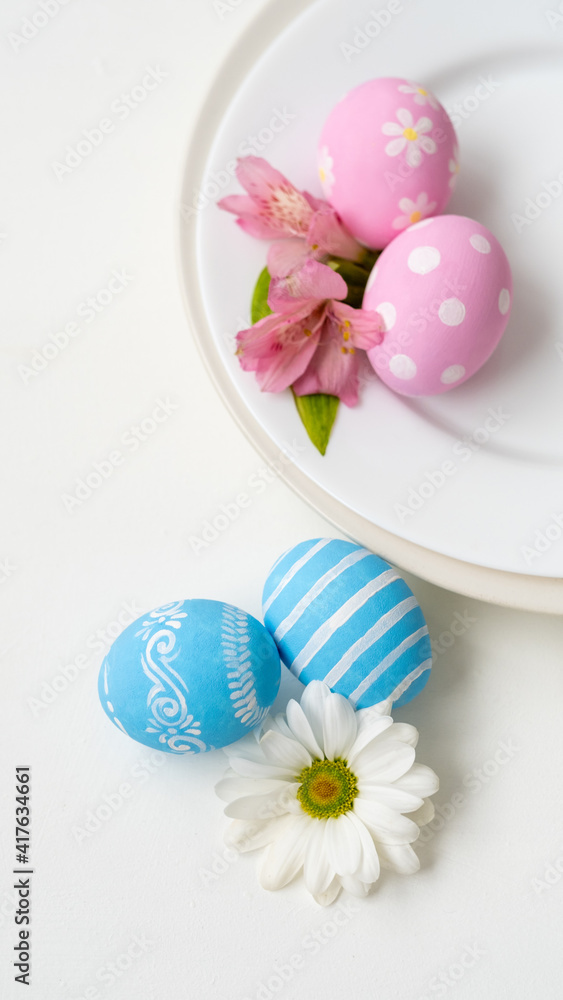 Easter dinner. Holiday celebration. Festive table. Pink blue color painted egg with polka dot stripe minimal design Spring flower composition served in plate isolated on white background.