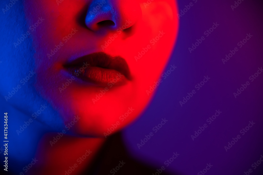Fototapeta premium Close-up portrait of beautiful young woman with short hair in neon light. Girl with sensual lips in ultraviolet light.