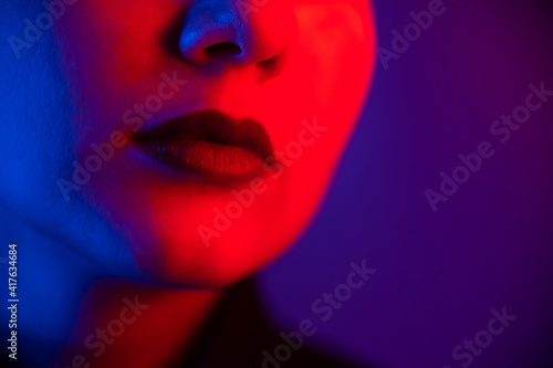 Close-up portrait of beautiful young woman with short hair in neon light. Girl with sensual lips in ultraviolet light.