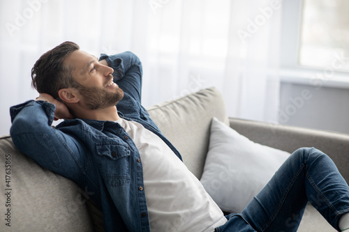 Closeup of carefree bearded man relaxing on couch at home