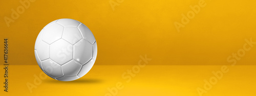 White soccer ball on a yellow studio banner