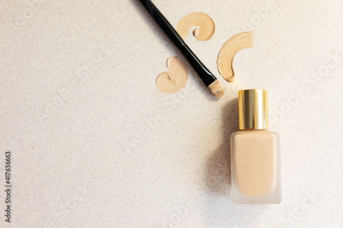 glass bottle with make up foundation on a light background with brush and smears . Copy space