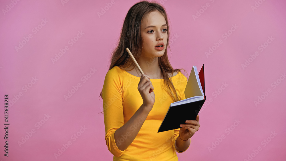 thoughtful teenage girl holding notebook and pen isolated on pink thoughtful teenage girl holding notebook and pen isolated on pink