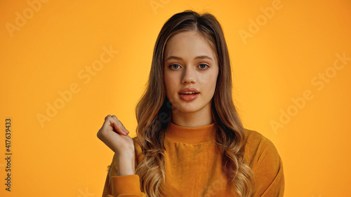 teenage girl in sweater looking at camera isolated on yellow