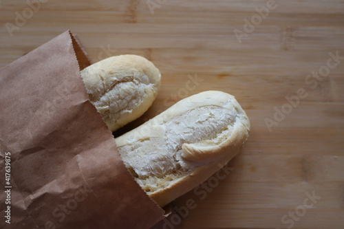 Two baguettes in a paper bag lie on a wooden board. selectiv focus. photo