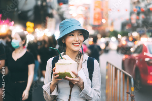 Canvas Print Young adult asian foodie woman backpack traveller eating coconut juice at china town street food