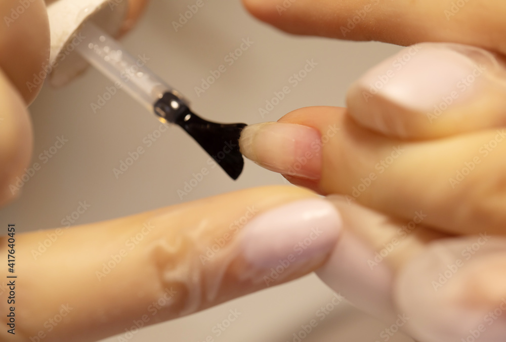 Nail polish woman to a beautician.Treatment hand and nail care the woman to a beautician for a manicure. Selective focus. Nail polish woman to a beautician.Treatment hand and nail care the woman to a beautician for a manicure. Selective focus.