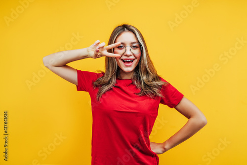 Portrait of a modern female student in transparent glasses on a yellow background with space for text. Studio photo