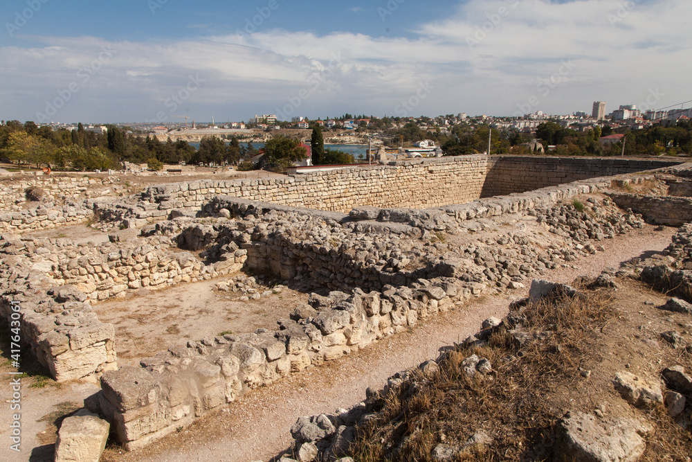 Ruins of ancient buildings in the city of Chersonesos and Sevastopol in the distance. Travel concept.