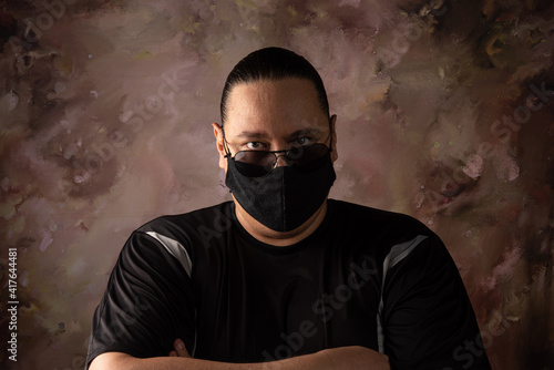 Portrait of brazilian man wearing mask against covid-19 and dark glasses, abstract background, selective focus