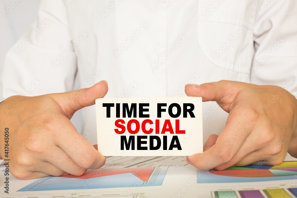 a man in the office holds a card with text TIME FOR SOCIAL MEDIA . business concept a man in the office holds a card with text TIME FOR SOCIAL MEDIA . business concept