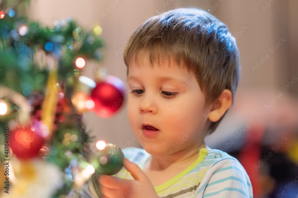 The boy decorates the Christmas tree. Children in Xmas